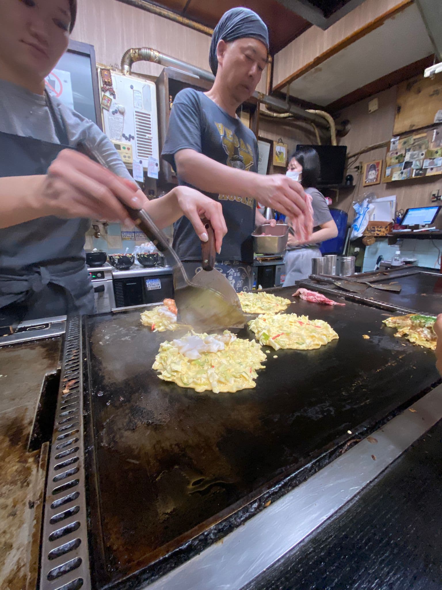 La plancha del okonomiyaki en plena acción, con el local trabajando a buen ritmo.