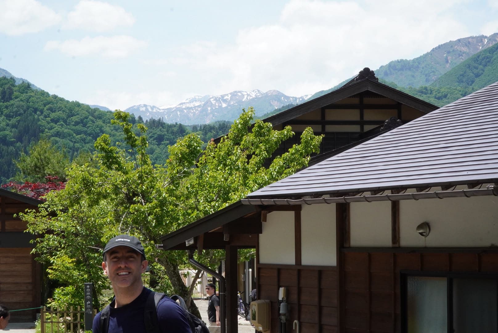 Otra vista luminosa de Miguel en Shirakawa-go, con montañas todavía nevadas al fondo.